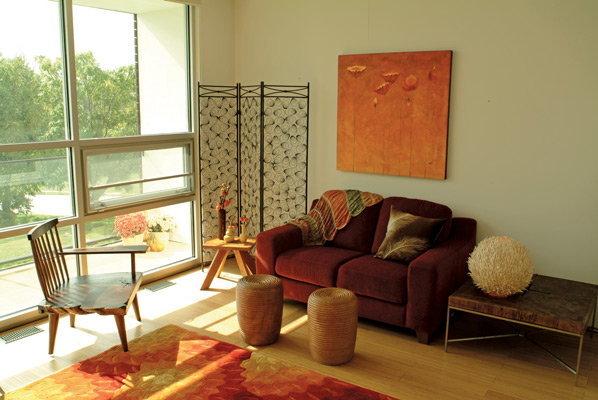 Warm-toned furnishings and natural shapes and images tie the home to the natural world. The Thai chair (left) and coconut lamp are from local store Black Bamboo; loveseat, screen and art by Blue Heron Furniture in nearby Lawrence; and reclaimed wood table by Kansas City’s Acronym Designs.